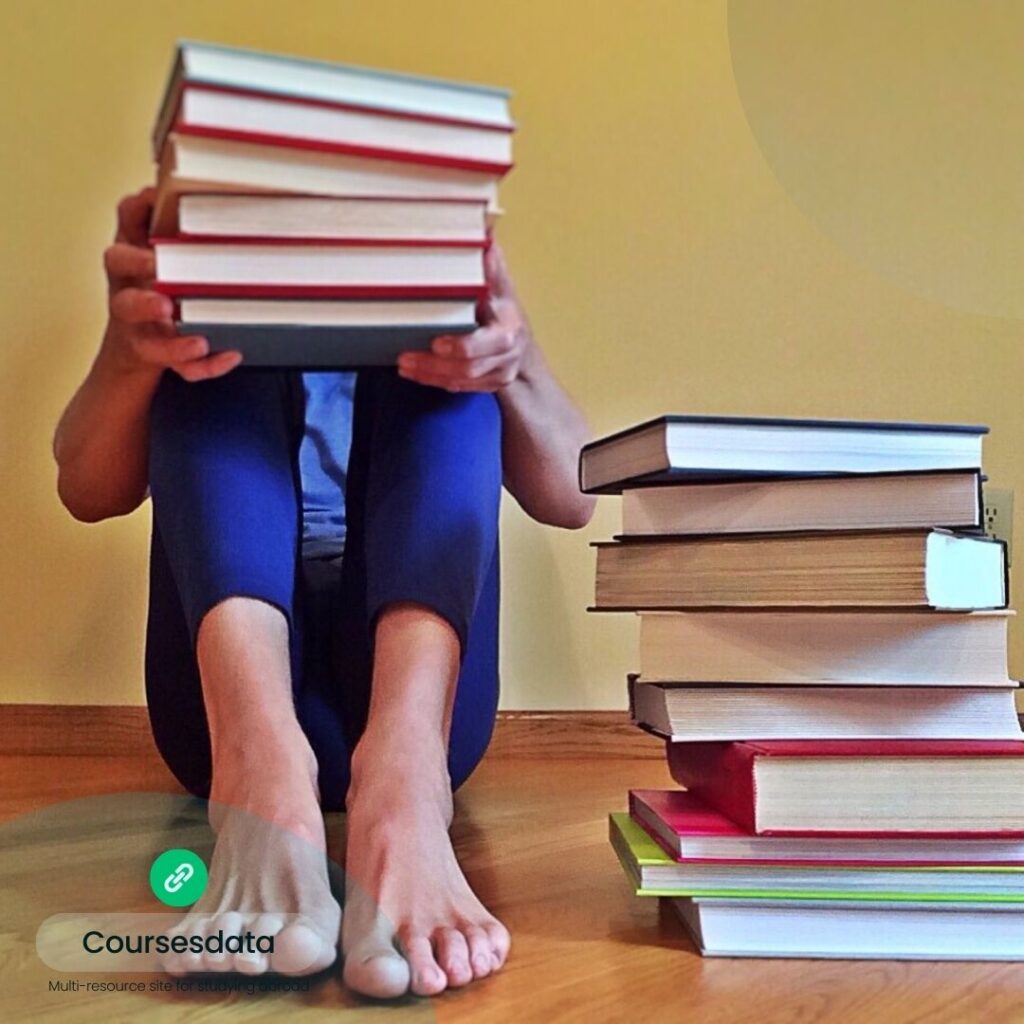 Person seated with stack of books.