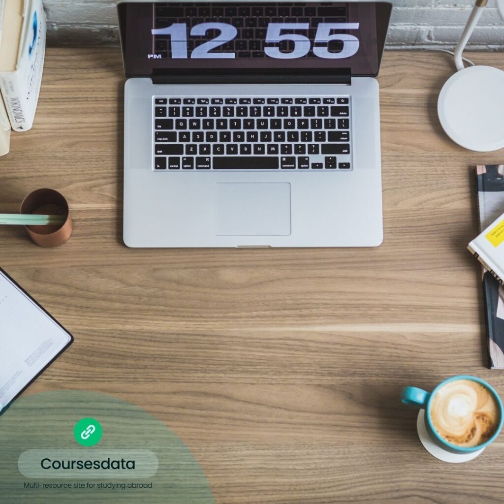 Laptop on wooden desk, clock.