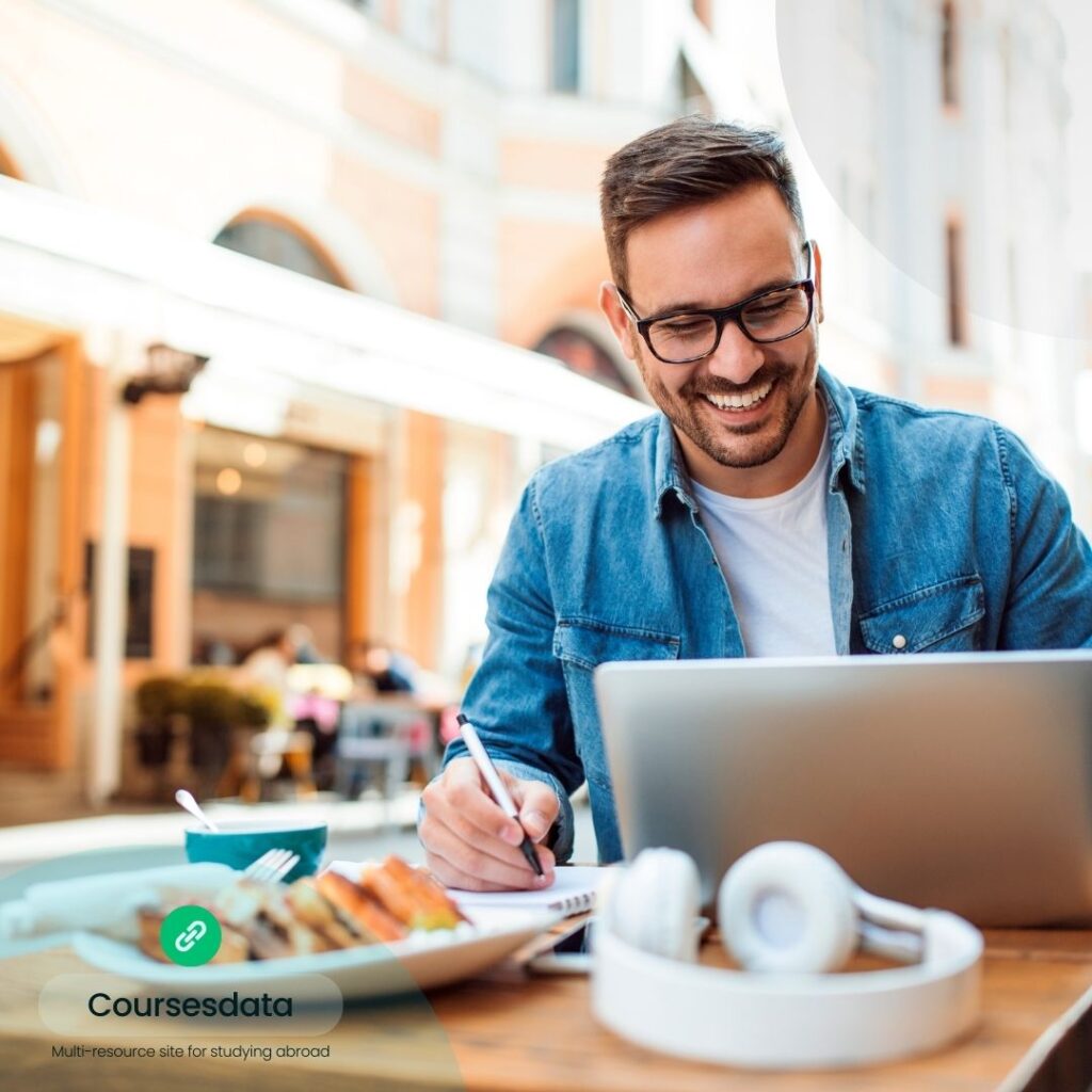 Smiling man studying outdoors, laptop.