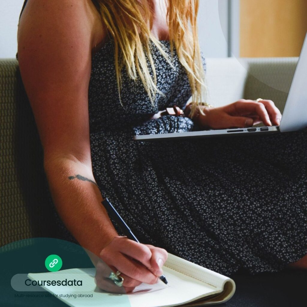 Woman writing notes, using laptop.