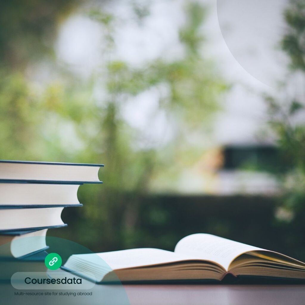 Stacked books beside open book.