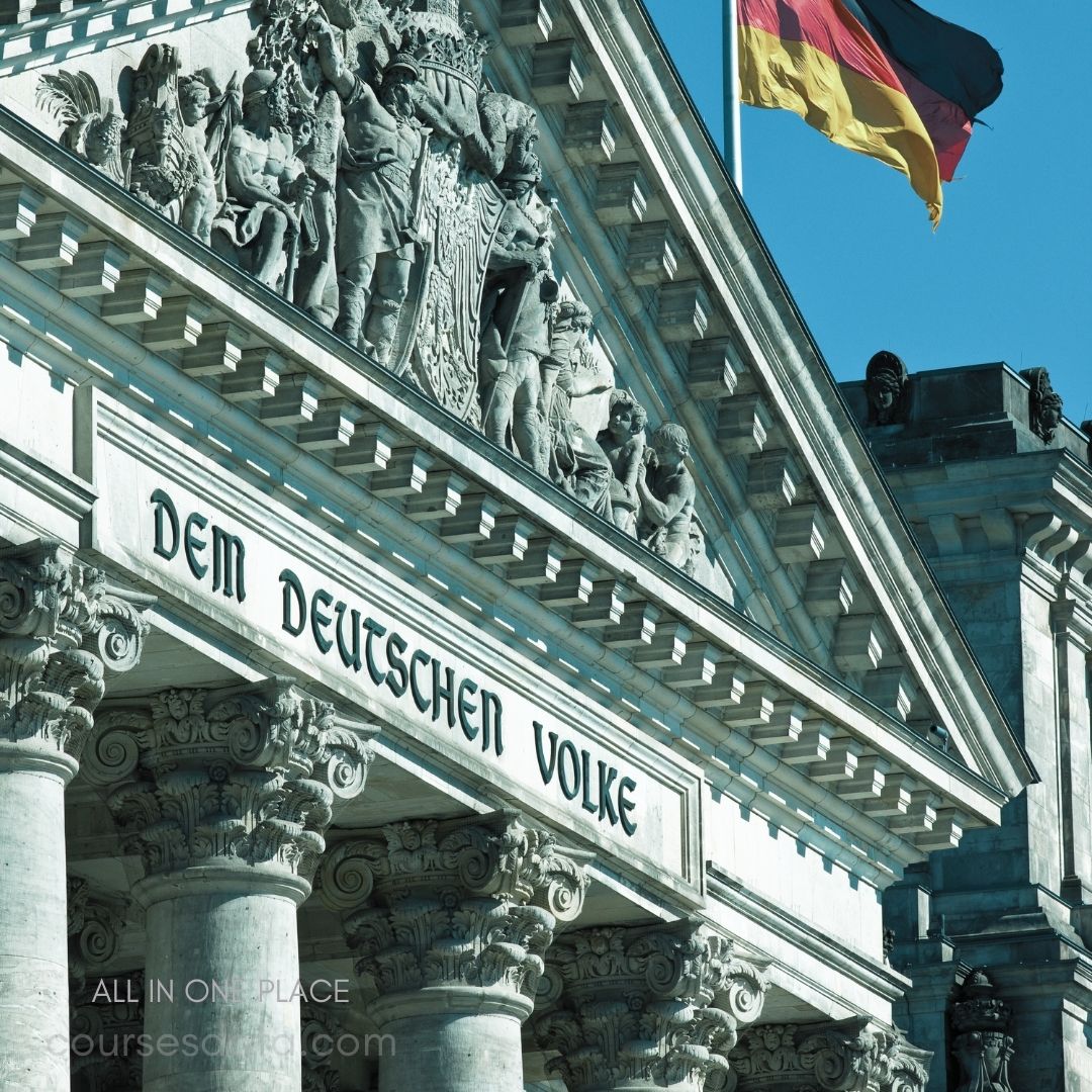 German parliament building facade. "Dem Deutschen Volke" inscription. Sculptural reliefs above columns. German flag waving above. Classic architectural details prominent.
