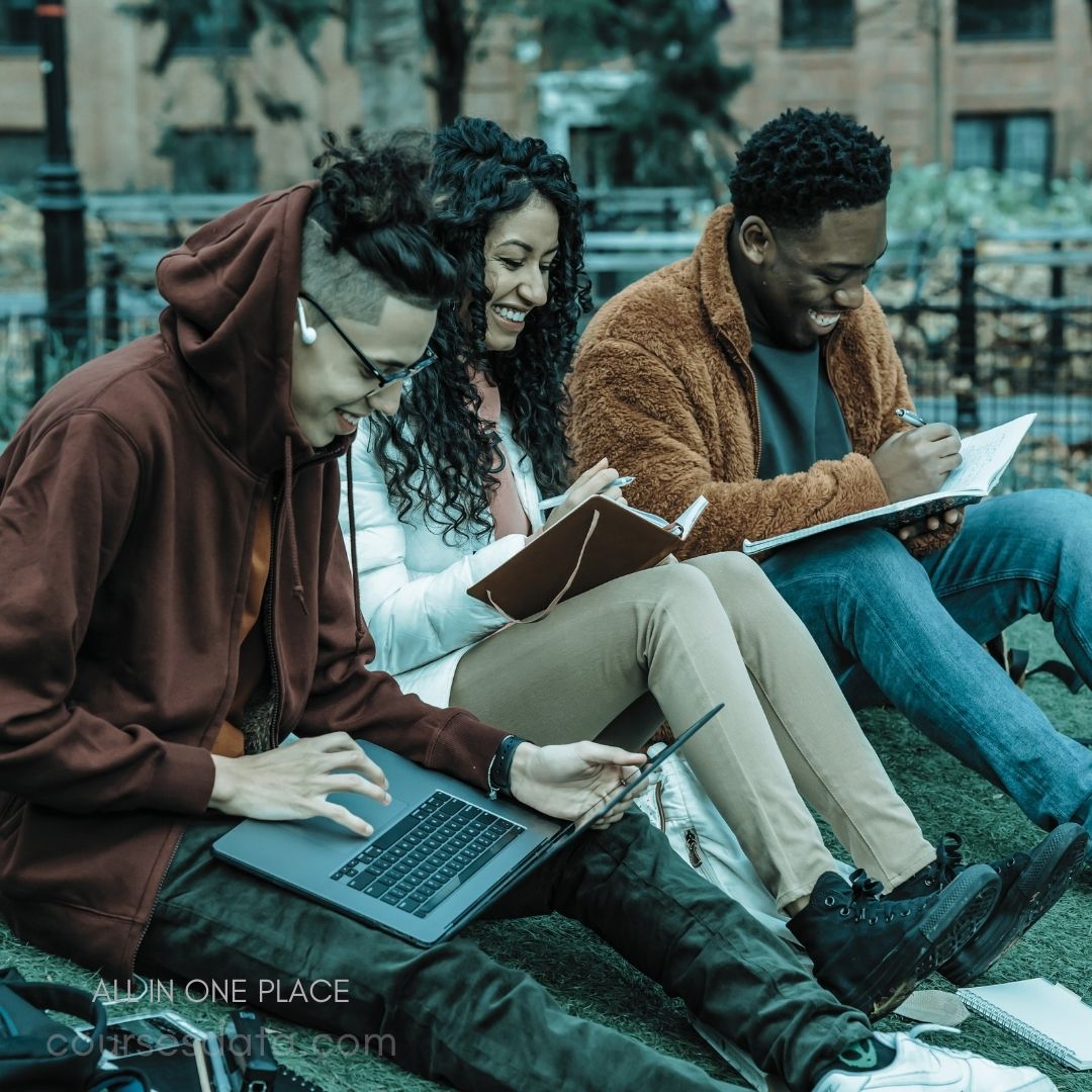 Three students studying together outdoors. Laughter and engagement are evident. Laptops and notebooks in use. Cozy clothing in autumn setting.