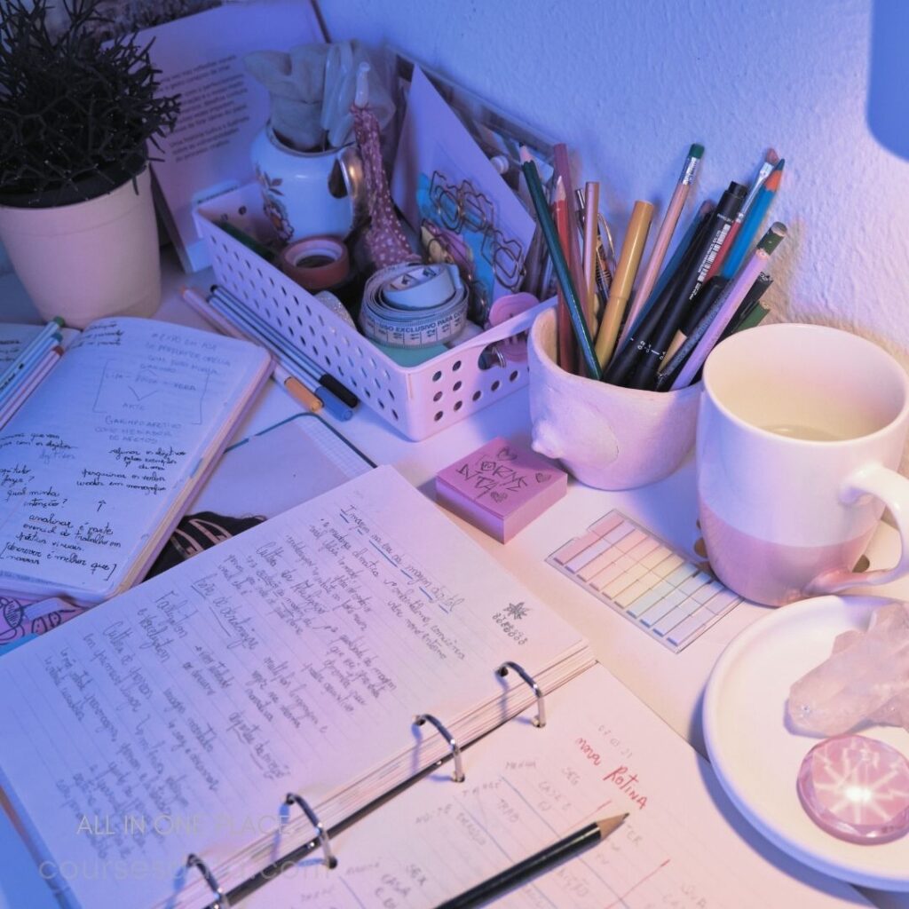 Desk with notebooks and stationery. Colorful pens in a holder. Cup of water beside notes. Succulent plant and decorative items. Soft purple lighting ambiance.