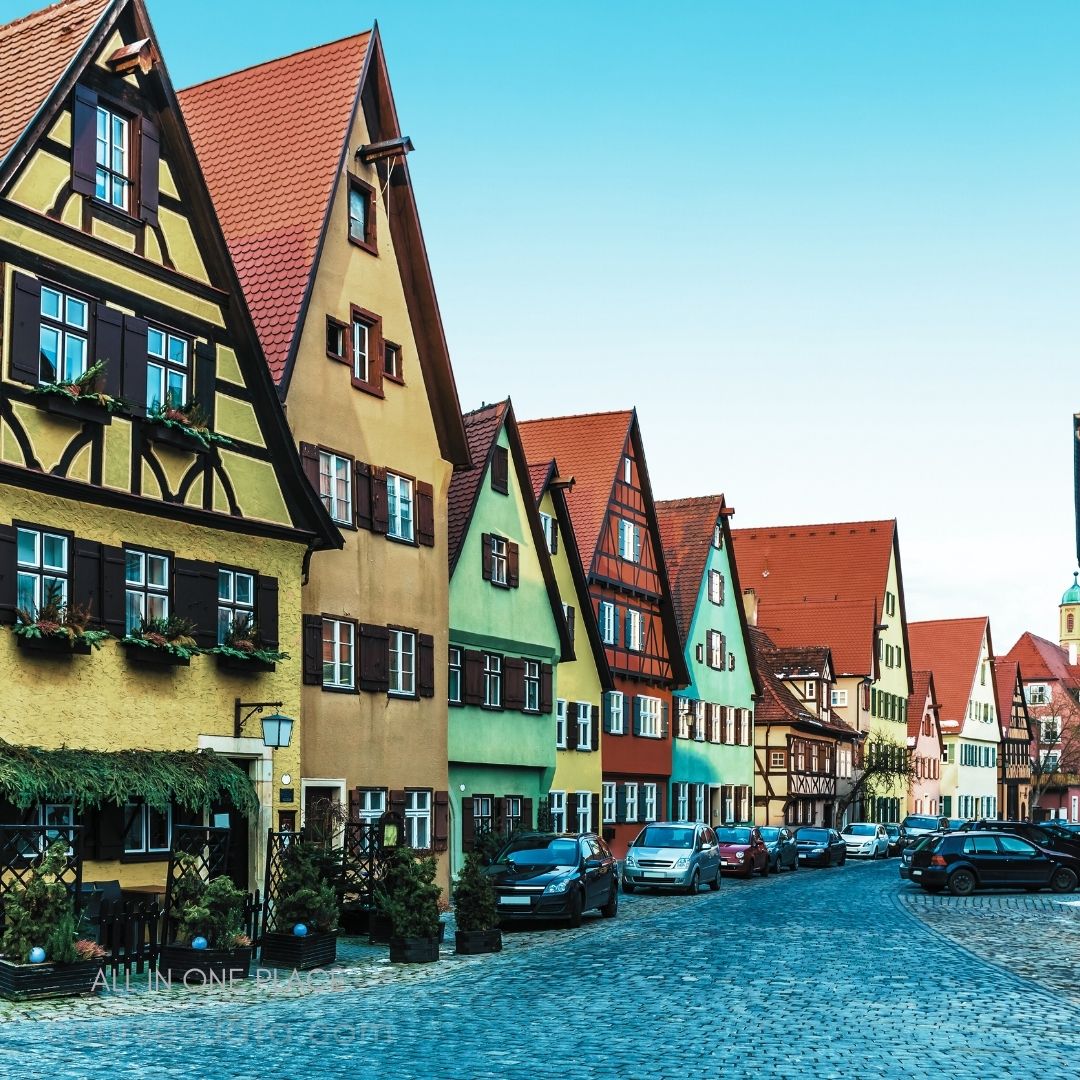 Charming colorful houses lining street. Cobblestone road and parked cars. Clear blue sky above.