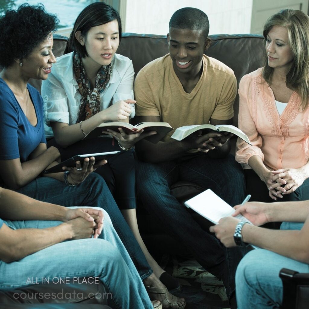 Group discussing books together. Diverse individuals sitting closely. Open books in hands. Casual indoor setting, warm light. Engaged expressions, sharing ideas.