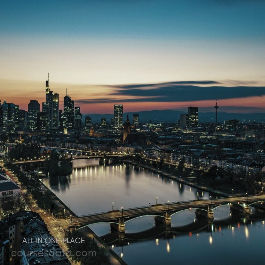 Frankfurt skyline at dusk River reflecting city lights Bridges crossing calm water Tall buildings against colorful sky Historic church in foreground