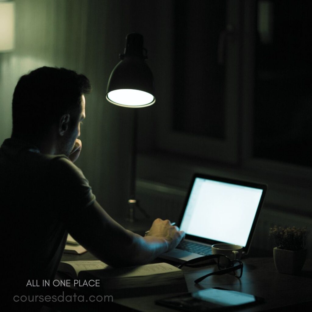 Man working on laptop, dim light.