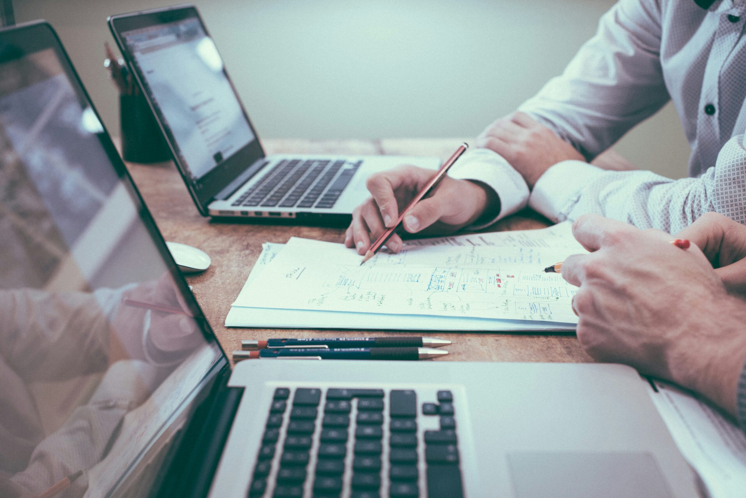 person holding pencil near laptop computer+ Risk Management in Investments