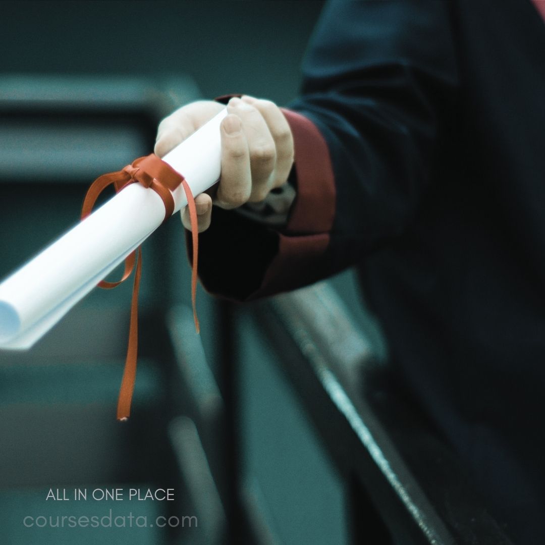 Person holding diploma scroll. Red ribbon tied around scroll. Formal attire with dark jacket. Dimly lit background setting. Prominent text: "ALL IN ONE PLACE."