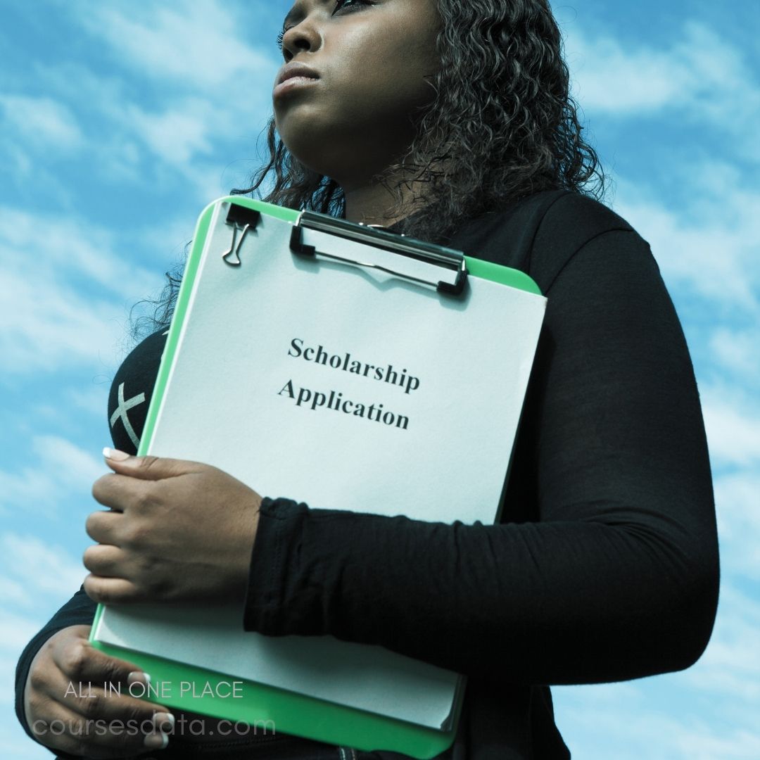 Person holding scholarship application. Hopeful expression, blue sky. Clipboards with green folder.