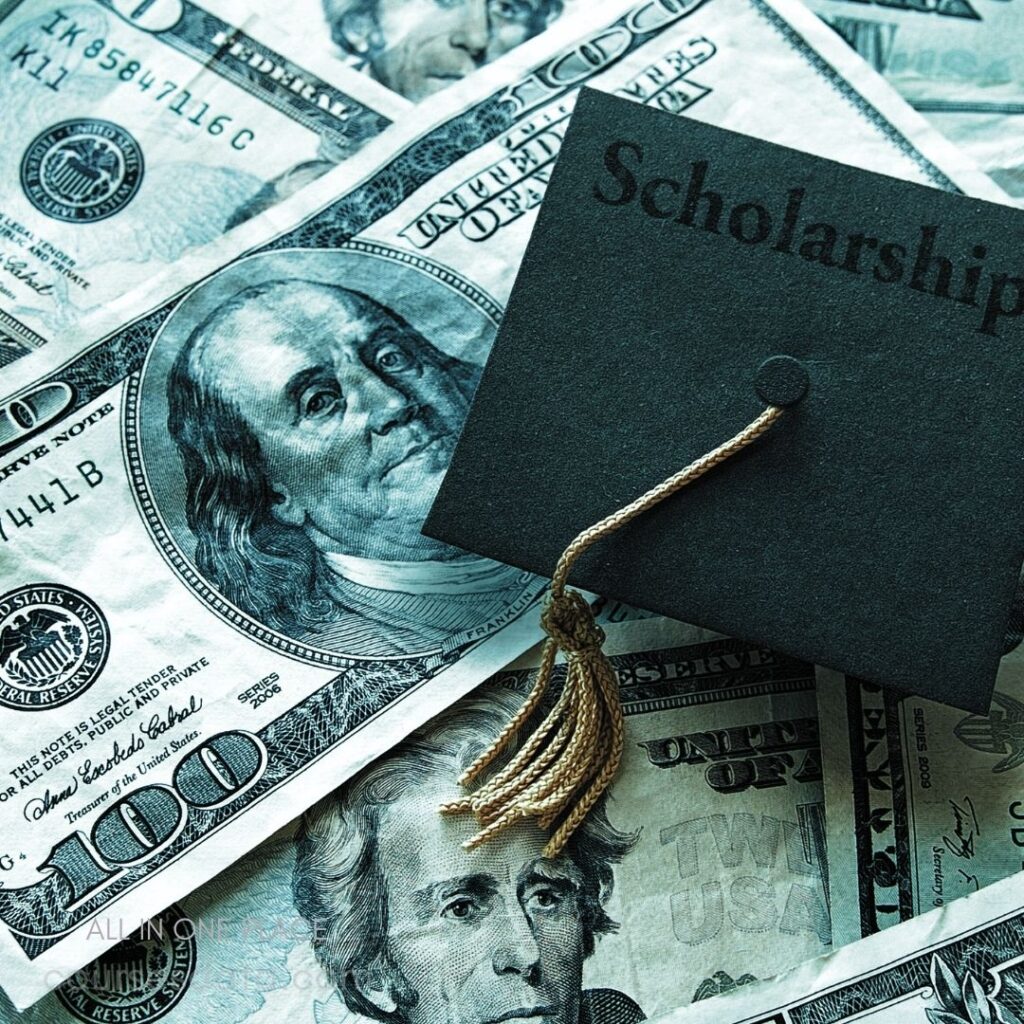 Graduation cap on money. "Scholarship" text visible. Hundred-dollar bills background. Tassel hanging from cap.