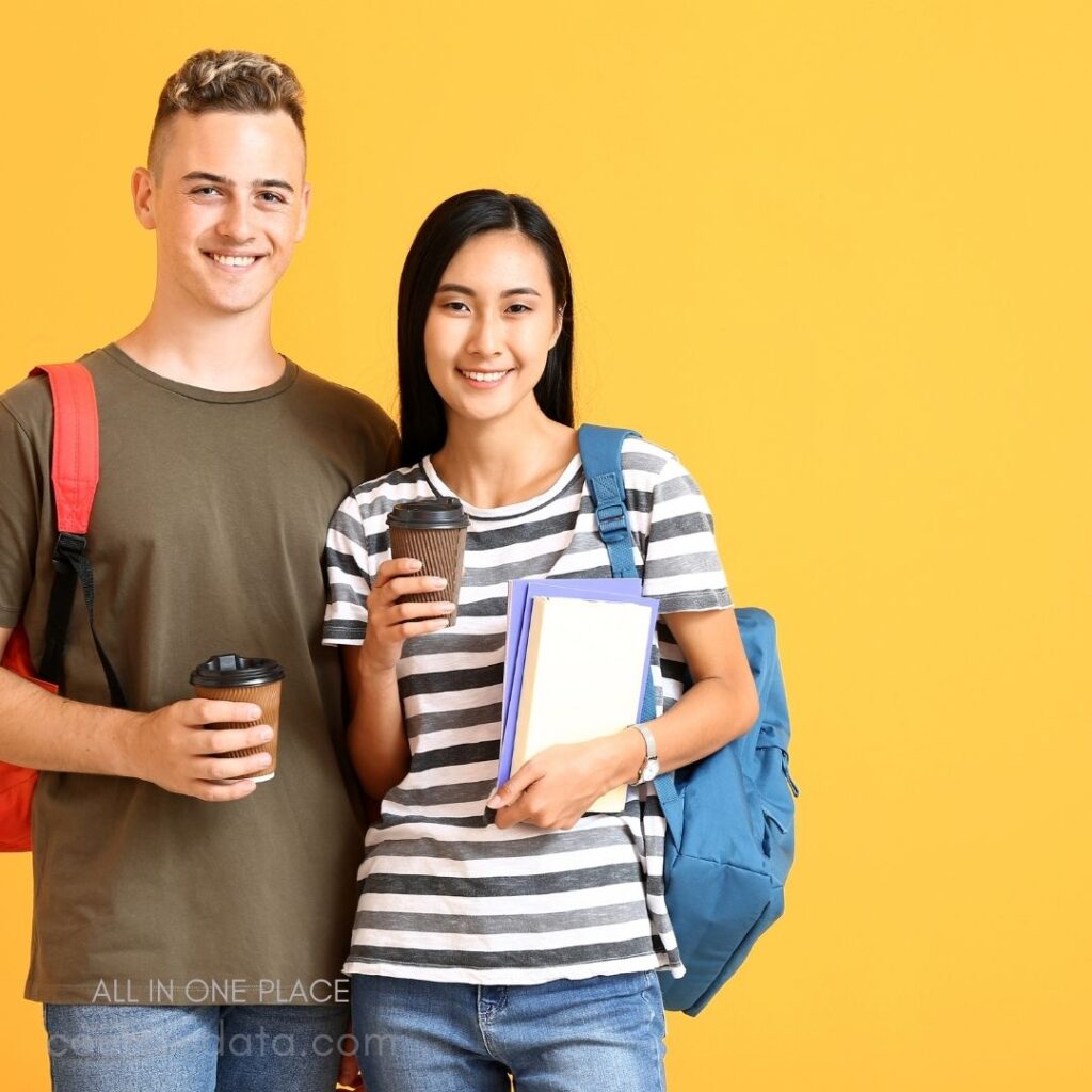 Smiling students against yellow background. Male with coffee and backpack. Female holding coffee and books. Casual attire and cheerful expressions. Bright, vibrant, youthful atmosphere.