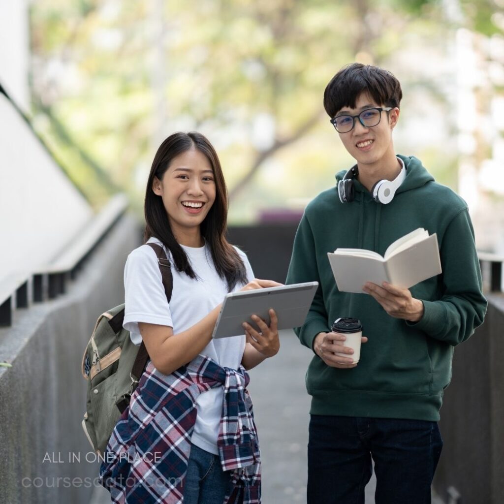 Two smiling students outdoors. Young woman holding tablet. Young man with book. Backpack and coffee cup. Casual clothing, green background.